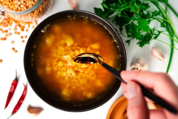 Sopa de guisantes sobre un fondo blanco. Sopa de guisantes en un tazón negro. Perejil, pan. Cuchara. Foto de alta calidad