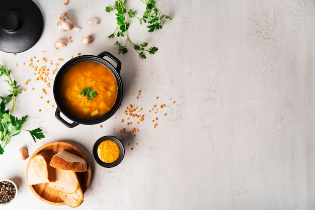 Sopa de guisantes sobre un fondo claro. Sopa en una cacerola negra. Un plato de sopa. Perejil, mezcla de pimientos, salsa, pan. Foto de alta calidad