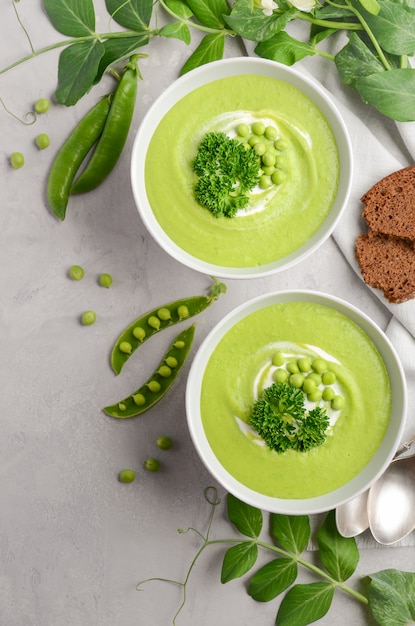 Sopa de guisantes verdes en cuencos en el fondo concreto o de piedra gris, visión superior, endecha plana.