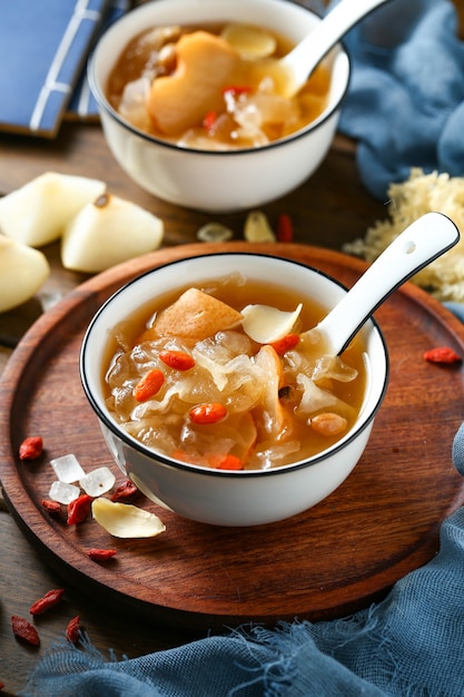 Sopa de hongos blancos y pera en un tazón blanco sobre placa de madera