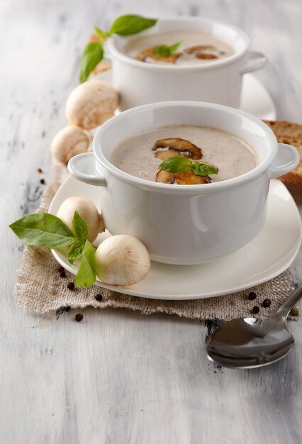 Sopa de hongos en ollas blancas en una servilleta con fondo de madera