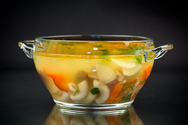 Foto sopa de hongos vegetariana cocida con verduras y pasta en un plato aislado sobre un fondo negro