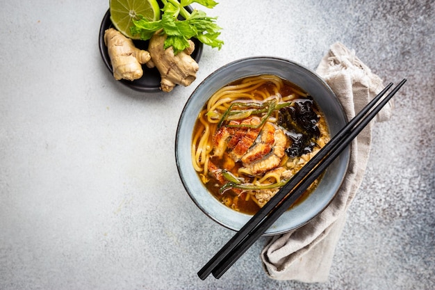 Sopa japonesa com enguia frita yanagawa nabe em uma tigela na vista superior de fundo cinza