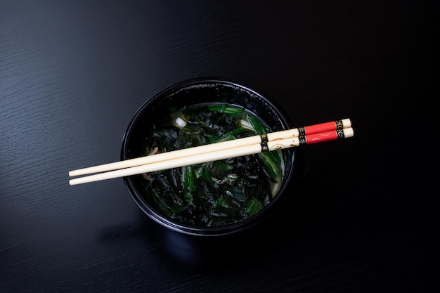 Foto sopa japonesa y palos en mesa de madera