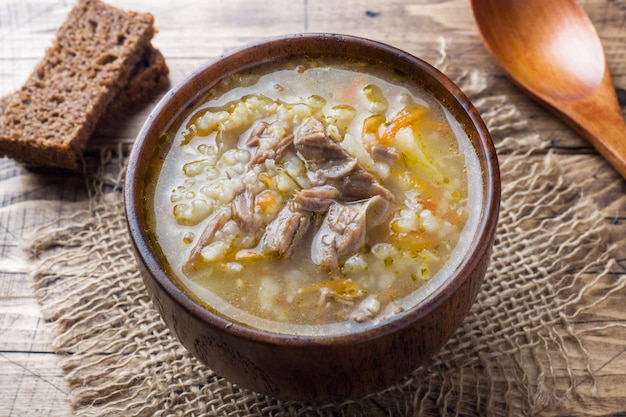 Sopa kharcho com carne e arroz na mesa de madeira