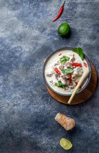 Sopa de leche de coco con champiñones de pollo tailandés tom kha gai en un tazón con especias tailandesas