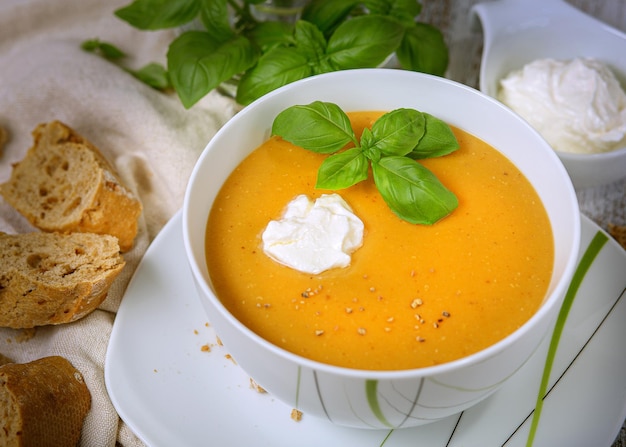 Sopa de lentejas con hojas de espinacas con crema agria en un recipiente blanco sobre un fondo claro. Vista superior