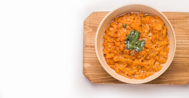 Sopa de lentejas indias Dhal con cilantro en un recipiente sobre una plancha de madera