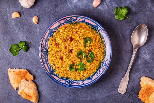 Sopa de lentejas en un plato adornado con cilantro y especias