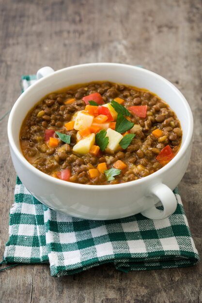 Sopa de lentejas en un recipiente sobre la mesa de madera