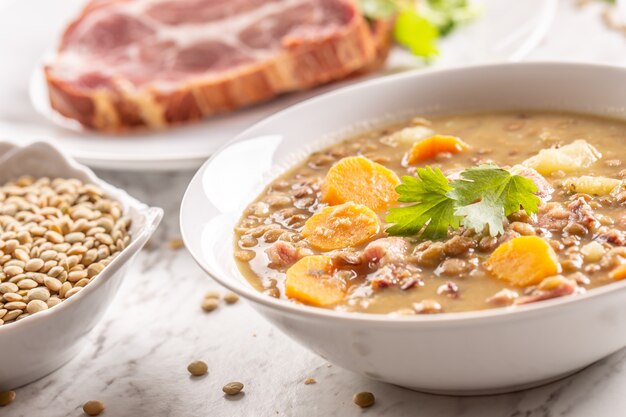 Sopa de lentejas con trozos de cuello de cerdo ahumado, zanahorias, patatas y cilantro. Comida tradicional eslovaca, checa o de Europa del Este.