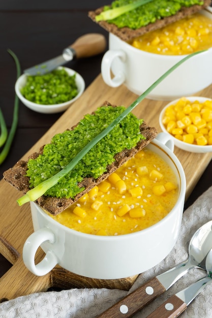 Sopa de maíz con paté de ajo fresco en un tazón blanco Comida saludable sobre fondo de madera Cocina vegana