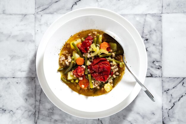 Sopa minestrone italiana de verão com tomate e pão caseiro em uma mesa de mármore