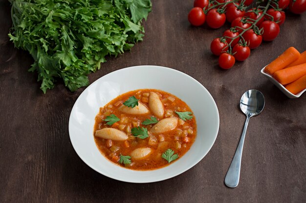 Sopa minestrone con pasta y hierbas. Comida italiana Fondo de madera oscura.