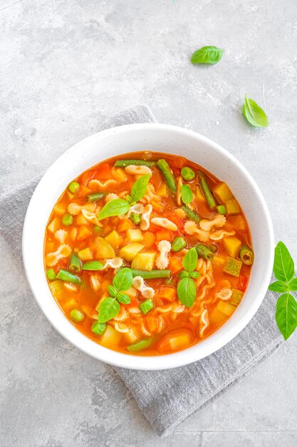 Sopa minestrone de verduras frescas y pasta en un bol sobre un fondo de hormigón gris Plato vegano