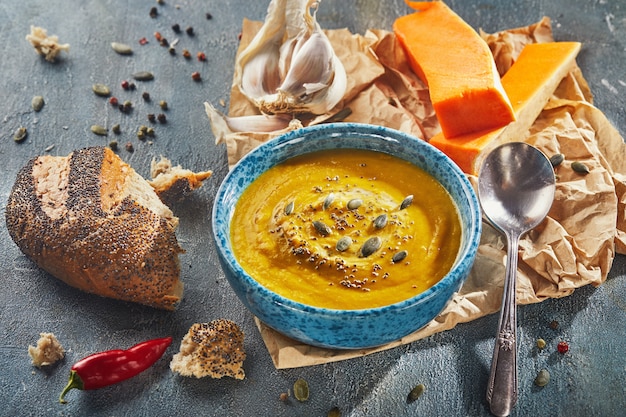 Sopa de naranja en un plato azul con semillas de calabaza y granos de chía