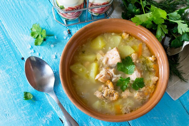 Foto sopa con orejas de salmón y pasteles abiertos con pescado rojo en el fondo de madera de la cocina