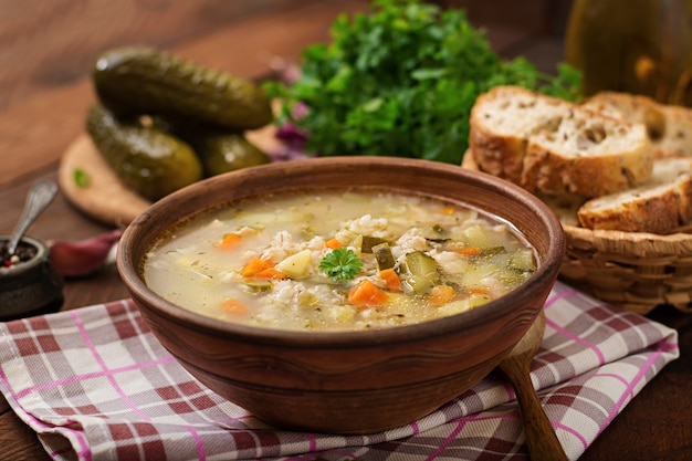 Sopa con pepinos conservados en vinagre y cebada de perla - rassolnik en un fondo de madera.