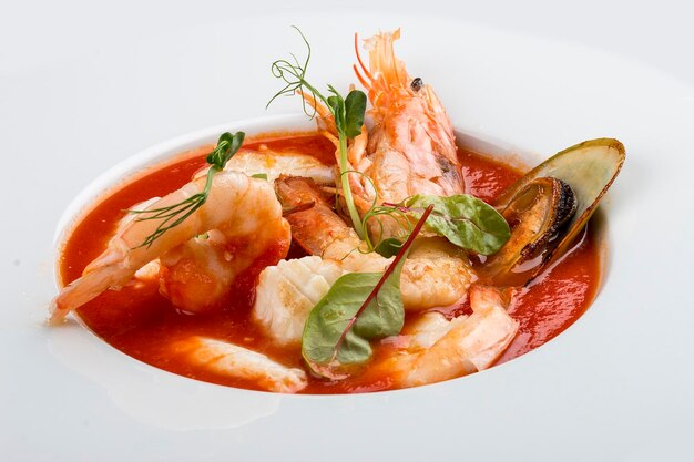 Sopa de pescado bullabesa francesa con camarones, mejillones y vieiras En un plato blanco sobre un fondo textil