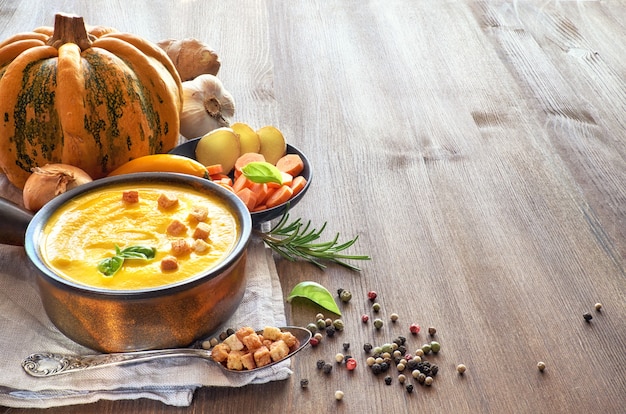 Sopa picante de calabaza con jengibre, chile, ajo y cebolla servida en sartén de cerámica, espacio