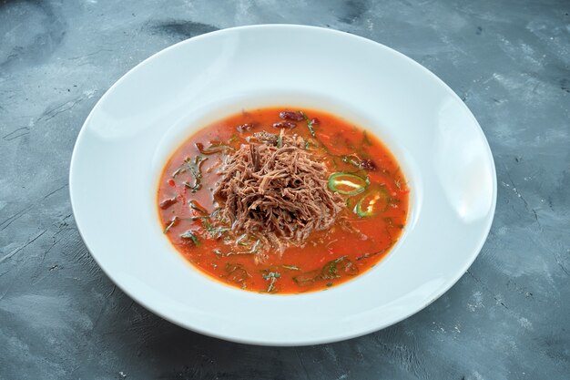 Sopa picante mexicana - chili con carne con rosbif en una placa blanca sobre un fondo gris