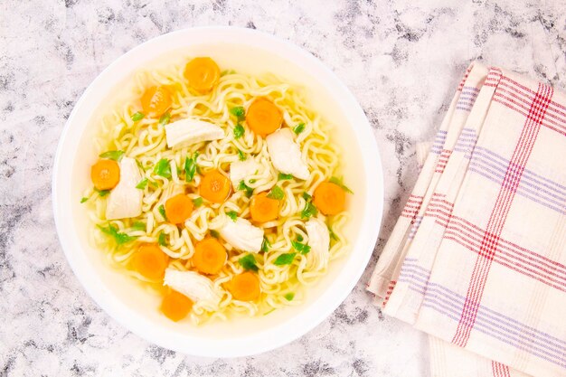 Sopa de pollo casera con fideos y verduras en un tazón blanco sobre un fondo gris Comida sana, cálida y cómoda