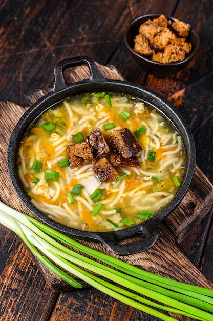 Sopa de pollo con fideos y verduras. Mesa de madera oscura. Vista superior.