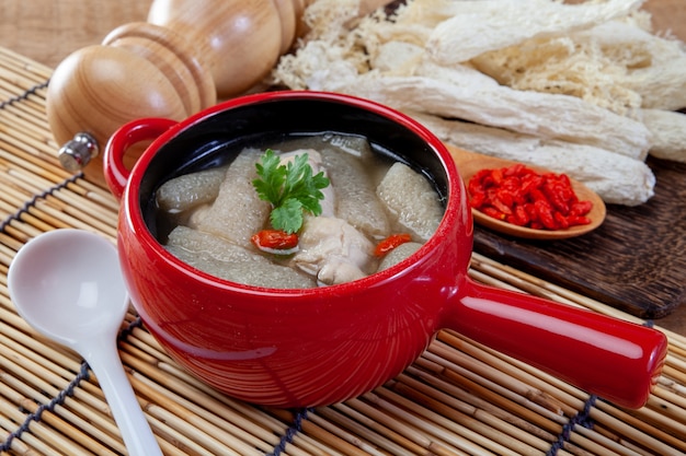 Sopa de pollo con hierbas chinas y bambú en un recipiente blanco.