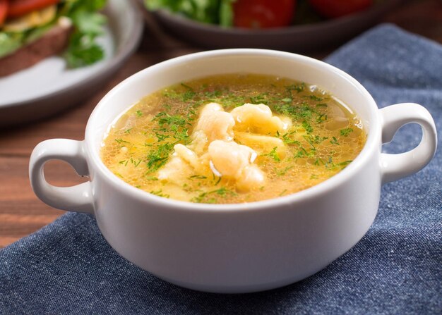 Sopa de pollo ñoquis de patata con hierbas frescas Fondo de madera