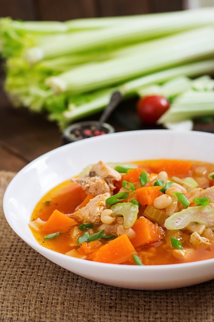 Sopa de pollo y tomate con calabaza, frijoles y apio en un tazón blanco