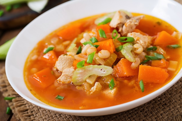 Sopa de pollo y tomate con calabaza, frijoles y apio en un tazón blanco