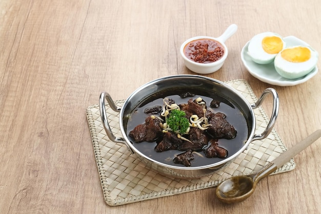 Sopa preta de carne tradicional da Indonésia de Rawon servida em uma tigela com pasta de pimenta de brotos de feijão mungo