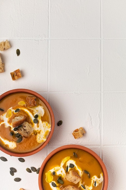 Sopa de puré de calabaza lista en tazas para dos sobre una mesa blanca