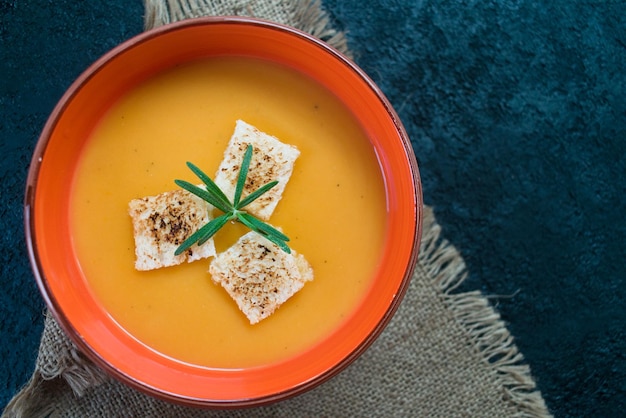 Sopa de puré de calabaza con picatostes de ajo sobre una mesa negra. Vista superior.