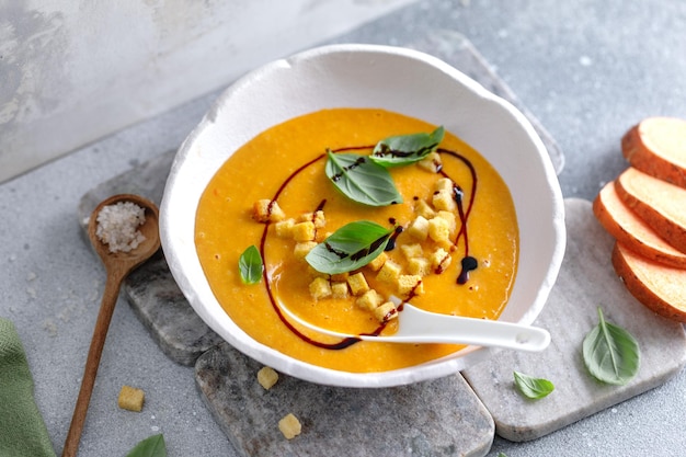 Foto sopa de puré de calabaza con picatostes y albahaca servida en un tazón sobre la mesa