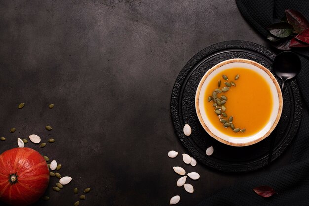 Sopa de puré de calabaza con semillas y semillas de sésamo en una placa de luz sobre una pizarra negra, vista superior