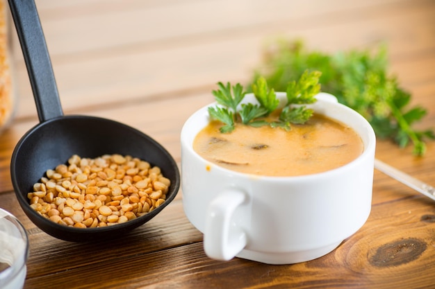 Sopa de puré de guisantes secos cocidos con champiñones en un recipiente sobre una mesa de madera oscura