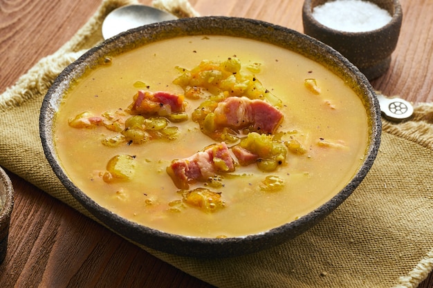 Sopa quente de inverno com ervilhas verdes picadas, carne de porco, bacon, fumado na mesa de madeira marrom escura