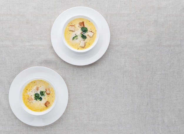 Sopa de queso con brócoli en una placa blanca sobre un mantel de lino blanco