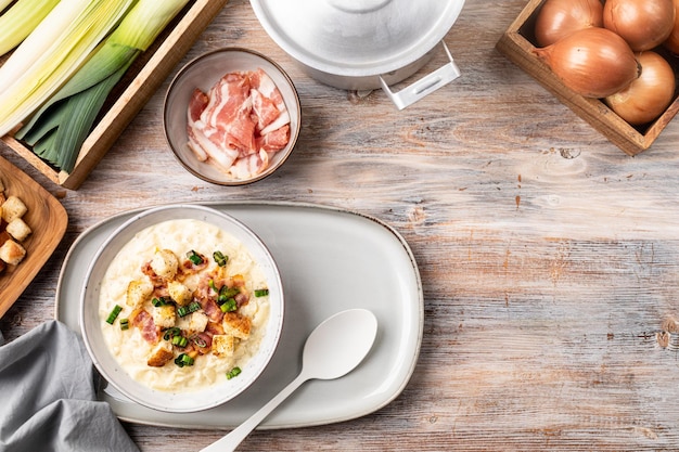 Sopa de queso con crutones y tocino en un bol sobre una mesa de madera