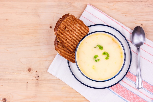 Sopa de queso en un plato blanco con pan tostado