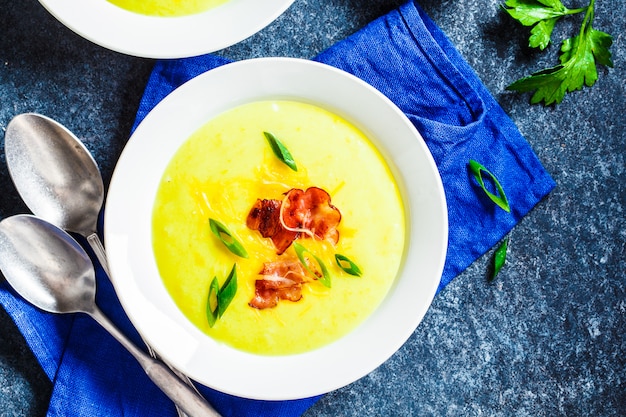 Sopa de queso con tocino y cebolla verde en plato blanco