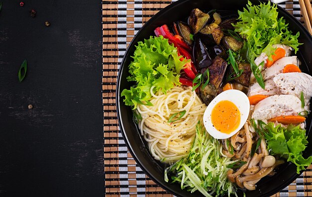 Sopa de ramen japonesa con huevo de pollo, setas shimeji y berenjenas sobre un fondo de madera oscura Sopa de sumo Chanko nabe Vista superior