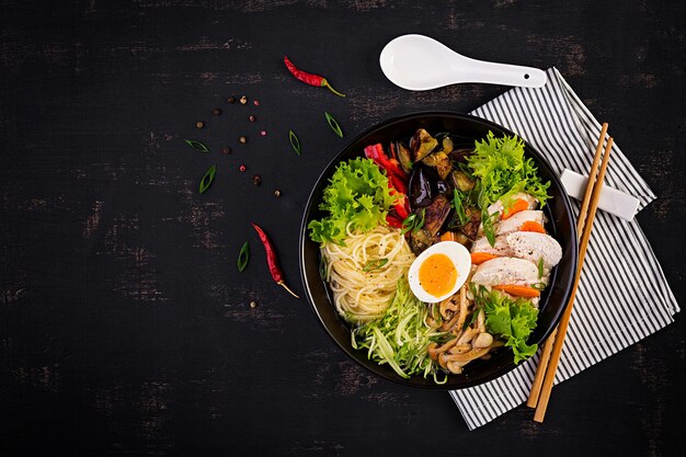 Sopa de ramen japonesa con huevo de pollo, setas shimeji y berenjenas sobre un fondo de madera oscura Sopa de sumo Chanko nabe Vista superior