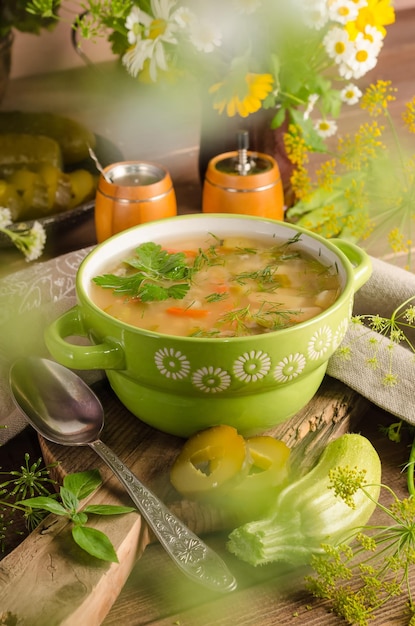 Sopa rassolnik tradicional com picles em conserva em uma terrina verde sobre fundo de madeira