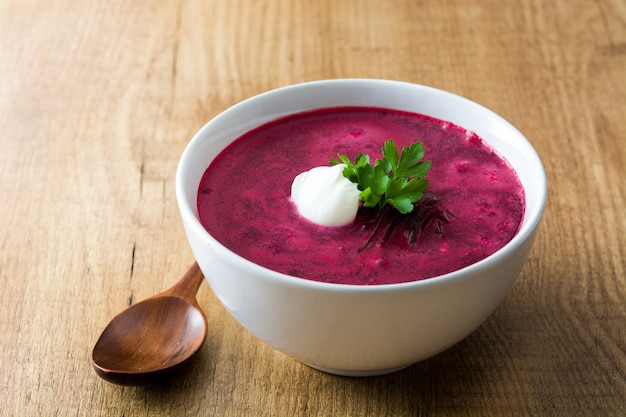 Sopa de remolacha en un tazón blanco sobre mesa de madera