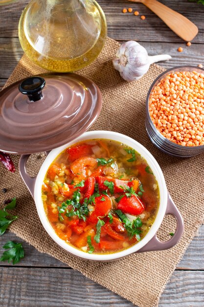 Sopa roja con lentejas y verduras en una mesa de madera. Comida sana, comida sana. Vista superior