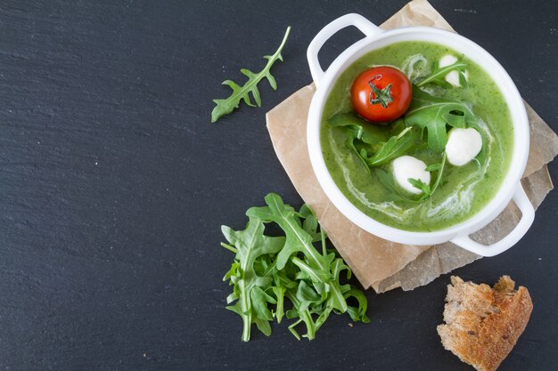 Sopa de rúcula y puré de tomates en un tazón blanco