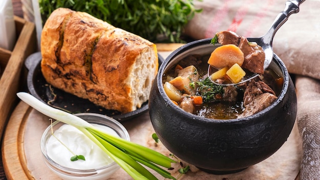 Sopa sabrosa con champiñones de carne y verduras en una olla con pan crujiente