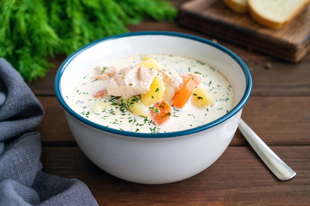 Sopa de salmón con crema de patatas, zanahorias y hierbas en un tazón de sopa Lohikeitto Copie el espacio